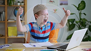 Boy on online class celebrate good grade, happy kid smile at laptop lesson Spbas. Kid get news