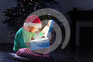 Boy open glowing present box near Christmas tree