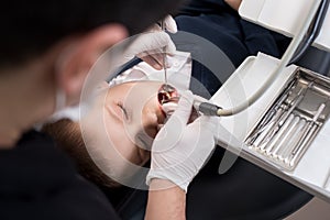 Boy with open mouth during drilling treatment at the pediatric dentist in dental clinic