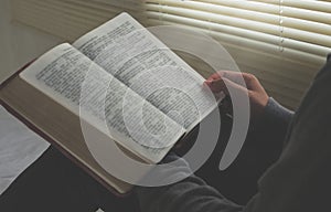 Boy opening Bible pages to study the Bible in the morning