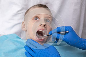 boy opens her mouth wide and pulls out long tongue. child shows his teeth soft palate and mouth to dentist. mouth is photo