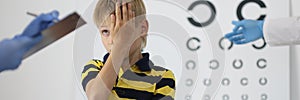 Boy at an ophthalmologist& x27;s appointment closes one eye and answers questions.