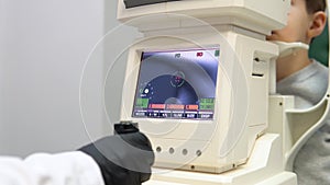 A boy in an ophthalmology clinic performs a vision test on special equipment