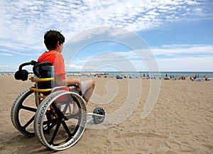 Boy with orange t-shirt sitting on the wheelchair with aluminum
