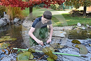 Boy helps cleaning the garden pond