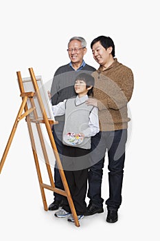 Boy painting with father and grandfather, studio shot