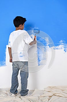 Boy painting wall with paint roller. Conceptual image