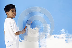 Boy painting wall with paint roller. Conceptual image