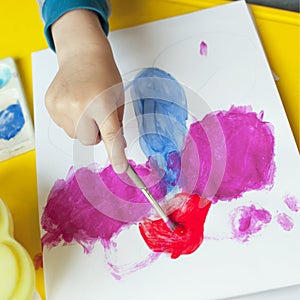 A boy paints a drawing on a piece of paper