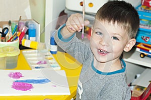 A boy paints a drawing on a piece of paper