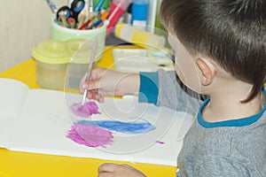 A boy paints a drawing on a piece of paper