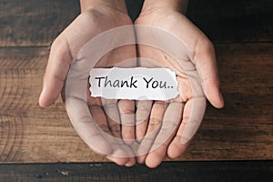 A boy with a paper note in his hands with the words THANK YOU