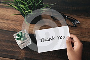 A boy with a paper note in his hands with the words THANK YOU