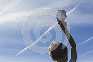 Boy with paper plane in his hand against blue sky. Low angle view