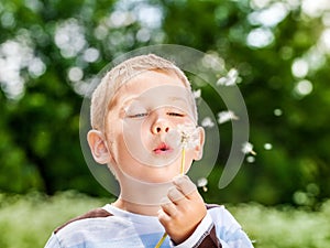 Boy in park blowing on dandelion