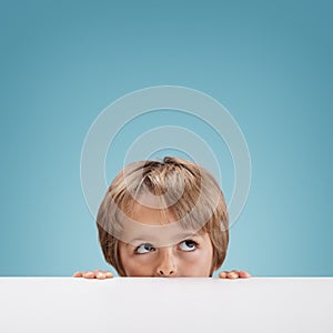 Boy peeking over a white board