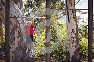 Boy performing pull-ups on bar during obstacle course