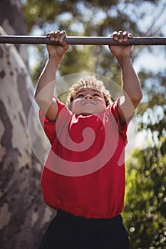 Boy performing pull-ups on bar during obstacle course