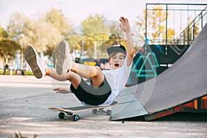 A boy performs tricks on a skateboard in a special area in the Park. A boy falls off a skate while riding in a skatepark