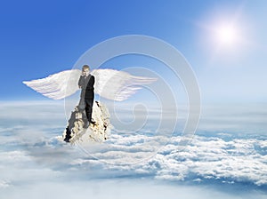 The boy with the phone in the costume with Angel Wings on a rock