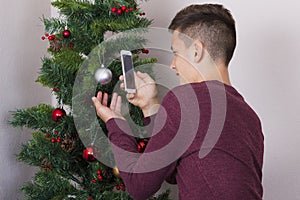 Boy with phone near New Year tree