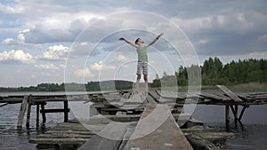 Boy is on the pier near lake enjoying the wind