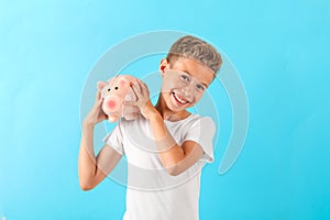 Boy with piggy bank against color background