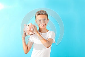 Boy with piggy bank against color background