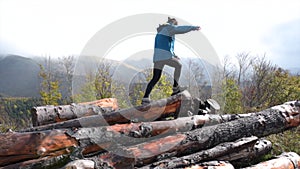 Boy with pigtails climbs up some logs and jumps down to the ground again