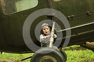 Boy in pilot helmet with glasses on green grass