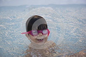 Boy with pink swimming goggles having fun in a hydromassage bath