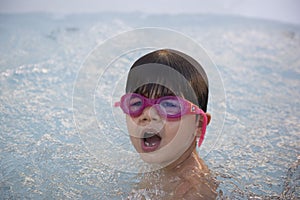 Boy with pink swimming goggles having fun in a hydromassage bath