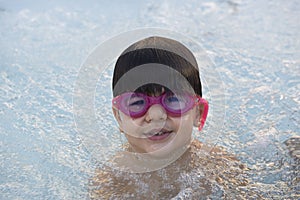 Boy with pink swimming goggles having fun in a hydromassage bath