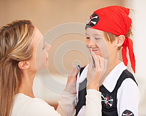 Boy, pirate costume and halloween in home, woman and face paint for happiness in childhood. Son, smile and mother with