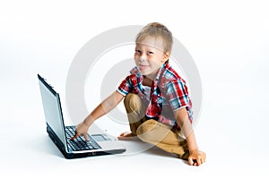 Boy in a plaid shirt with a laptop on a white background.