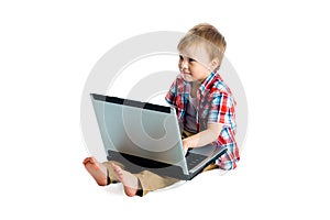 Boy in a plaid shirt with a laptop on a white background.