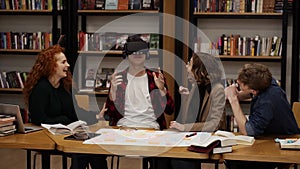 The boy in plaid shirt is wearing virtual reality glasses in the college library among his classmates. The concept of