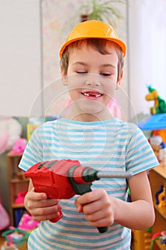 Boy in plastic helmet with toy drill