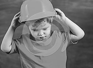 Boy play as builder or architect. Kid boy in orange hard hat or helmet, chalkboard on background. Childhood concept