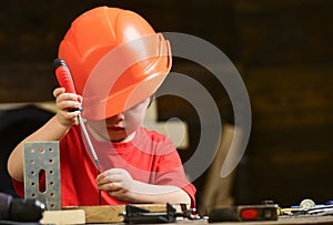 Boy play as builder or repairer, work with tools. Childhood concept. Kid boy in orange hard hat or helmet, study room