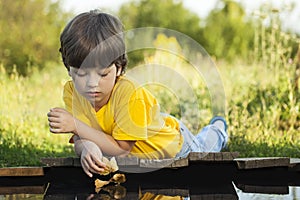 Boy play with autumn leaf ship in water, chidren in park play wi