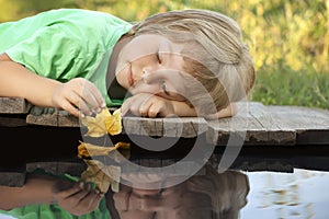 Boy play with autumn leaf ship in water, chidren in park play wi