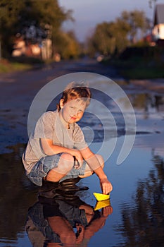 Boy play with autumn leaf ship in water, chidren in park play wi