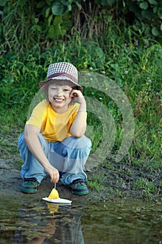 Boy play with autumn leaf ship in water, chidren in park play wi photo