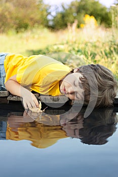 Boy play with autumn leaf ship in water, children in park play w