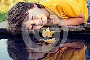 Boy play with autumn leaf ship in water, children in park play w