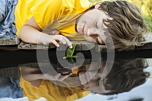 Boy play with autumn leaf ship in water, children in park play w