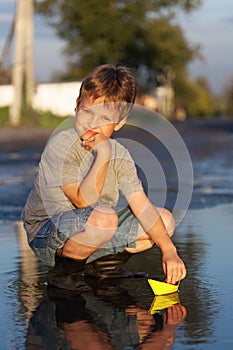 Boy play with autumn paper ship in water, chidren in park play w