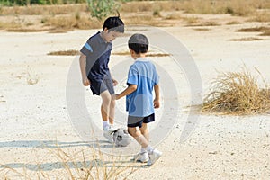 Boy play football on the dry soil ground