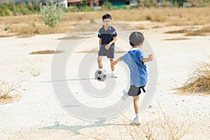Boy play football on the dry soil ground